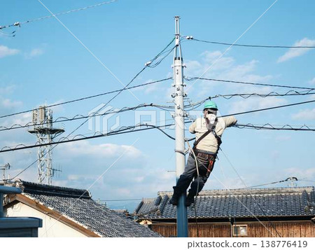 Electrical work on a utility pole in a residential area. Electrical work on a utility pole in a residential area. 138776419