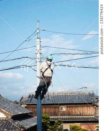 Electrical work on a utility pole in a residential area. 138776424