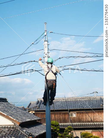 Electrical work on a utility pole in a residential area. Electrical work on a utility pole in a residential area. 138776430