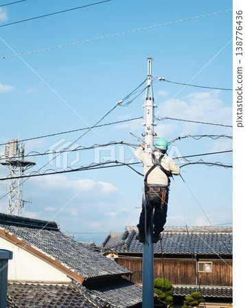 Electrical work on a utility pole in a residential area. Electrical work on a utility pole in a residential area. 138776436