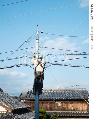 Electrical work on a utility pole in a residential area. Electrical work on a utility pole in a residential area. 138776449