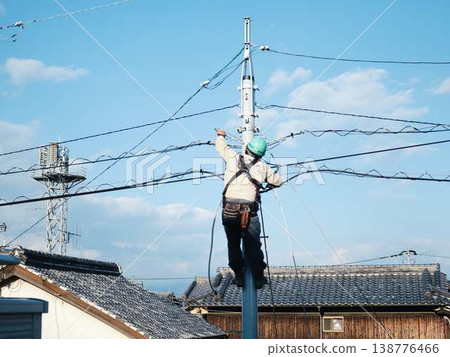 Electrical work on a utility pole in a residential area. 138776466