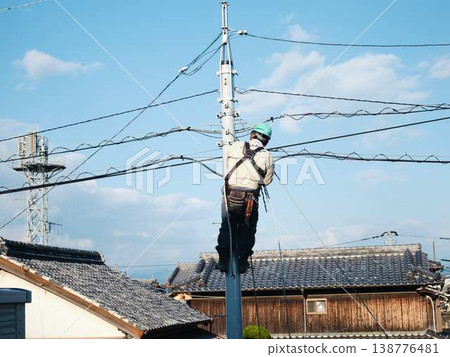 Electrical work on a utility pole in a residential area. 138776481