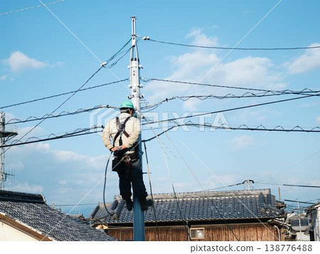 Electrical work on a utility pole in a residential area. 138776488