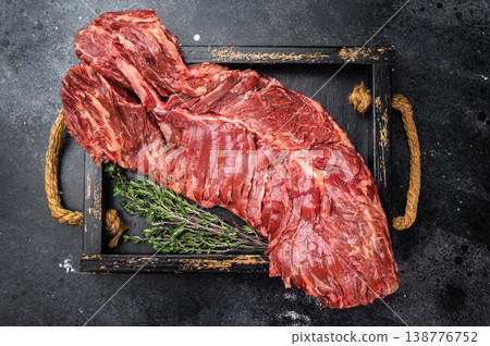 Raw beef hanger or onglet steak on black tray with rope handles over dark stone background, strong contrast and copy space 138776752