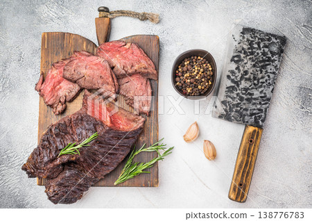 Cooked hanger steak diaphragm beef cut sliced with juicy medium doneness, herbs garlic and spices on board, clean light background Cooked hanger steak diaphragm beef cut sliced with juicy medium doneness, herbs garlic and spices on board, clean light background 138776783