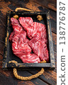 Closeup raw skirt beef steak with visible fibers and marbling on dark wooden background with rosemary and spices, uncooked protein ingredient for grilling 138776787