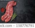 Closeup raw onglet hanger steak on metal grate over black textured surface, rich red meat with visible fibers and fat, ideal for barbecue and cooking 138776791