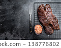 Grilled beef hanger steak onglet on metal rack with fork and coarse salt, dark stone background with copy space for barbecue concept 138776802