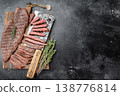 Juicy sliced outside skirt beef steak with herbs and knife on wooden board, grilled meat with visible fibers and medium rare doneness 138776814