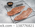 Grilled beef steaks on cooling rack with seasoning and pepper, juicy cooked meat ready to serve, homemade dinner or barbecue food concept 138776821
