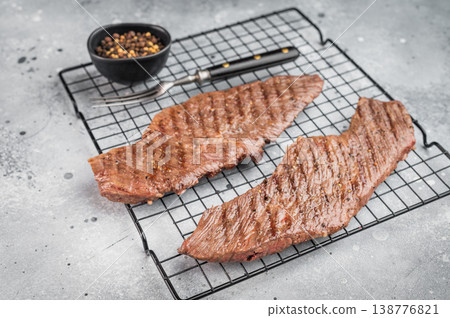 Grilled beef steaks on cooling rack with seasoning and pepper, juicy cooked meat ready to serve, homemade dinner or barbecue food concept Grilled beef steaks on cooling rack with seasoning and pepper, juicy cooked meat ready to serve, homemade dinner or barbecue food concept 138776821