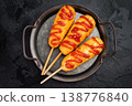 Golden corn dogs with ketchup topping served on plate with sauce, crunchy fast food snack on dark background 138776840