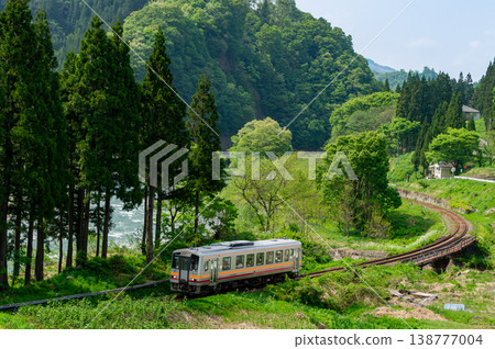 大糸線的一輛柴油車組沿著風景優美的姬川河小心翼翼地駛過一個彎道。 138777004