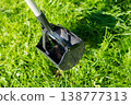 Pooper scooper on green grass in sunlight for pet waste cleanup 138777313