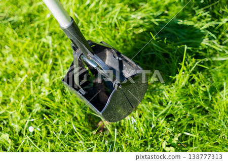 Pooper scooper on green grass in sunlight for pet waste cleanup Pooper scooper on green grass in sunlight for pet waste cleanup 138777313