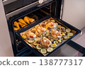 A baking tray with French-style pork, potatoes, mushrooms, and cheese, alongside baked chicken  138777317