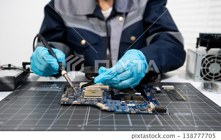 Computer Hardware Technician Repairing Motherboard with Soldering Iron in Electronics Lab. 138777705