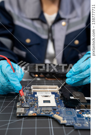 Computer Hardware Technician Repairing Motherboard with Soldering Iron in Electronics Lab. Computer Hardware Technician Repairing Motherboard with Soldering Iron in Electronics Lab. 138777711