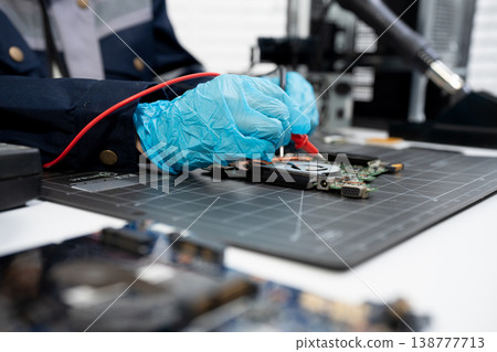 Computer Hardware Technician Repairing Motherboard with Soldering Iron in Electronics Lab. 138777713