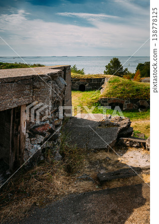 view of historic concrete bunkers and defensive structures built into the grassy landscape overlooking the Baltic Sea at the Suomenlinna fortress near Helsinki, Finland. 138778125