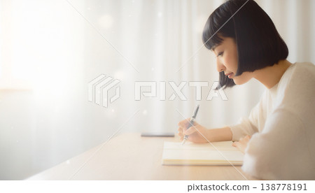 一位女性一邊在筆記本上寫作一邊思考，神情專注。 138778191