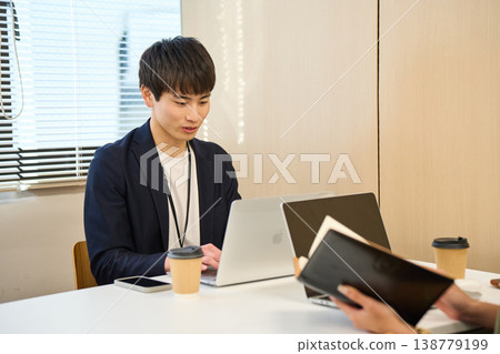Male and female employees working on their PCs or participating in web conferences in the meeting space. Male and female employees working on their PCs or participating in web conferences in the meeting space. 138779199
