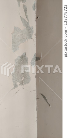 Peeling wall corner where two walls meet showing cracks and damaged plaster surface 138779722