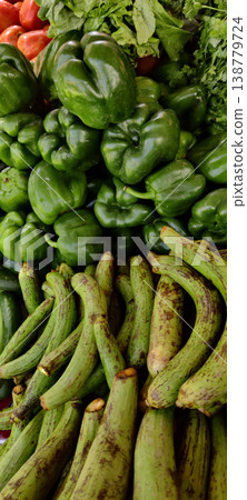 Ridge gourd stacked with green bell peppers and fresh vegetables in market showing organic produce display 138779724