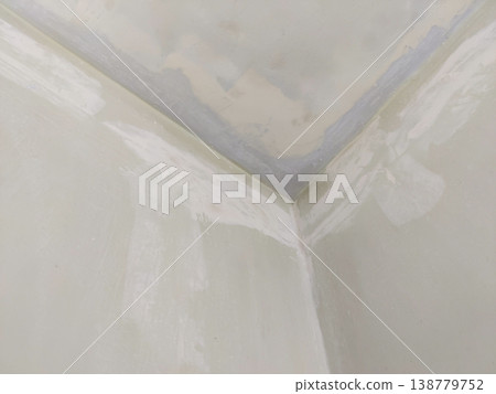 Wall and ceiling corner with putty repair and light off white base color before final paint 138779752