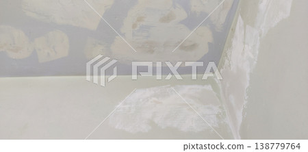 Wall and ceiling corner with putty patches and off white base color showing repair stage 138779764