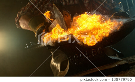 Close-up of blacksmith forging glowing hot iron on anvil with flying sparks 138779790