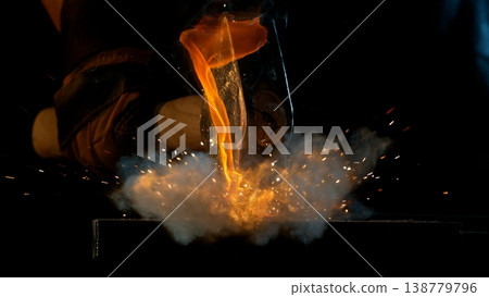 Close-up of blacksmith forging glowing hot iron on anvil with flying sparks Close-up of blacksmith forging glowing hot iron on anvil with flying sparks 138779796