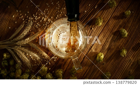 Pouring Beer into Pint Glass on Old Wooden Table, Top Down View. Pouring Beer into Pint Glass on Old Wooden Table, Top Down View. 138779820