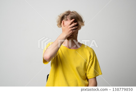 Frustrated young man covering his face with his hand, showing shame, stress, and disappointment, making a mistake or facing failure and embarrassment 138779850