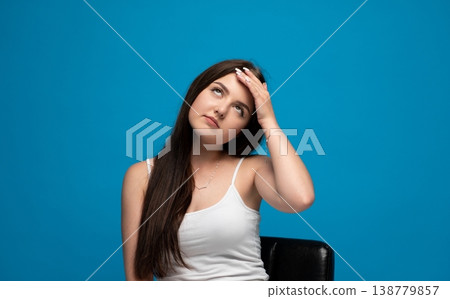 Young adult woman experiencing frustration and boredom, rolling eyes and holding hand to forehead, posing on a blue background Young adult woman experiencing frustration and boredom, rolling eyes and holding hand to forehead, posing on a blue background 138779857