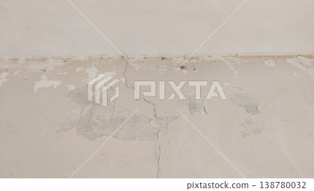 Peeling paint along cracked wall base showing signs of moisture decay 138780032