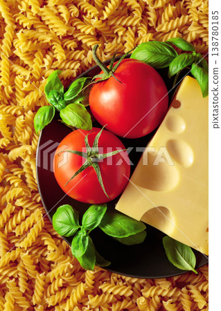 Uncooked fusilli pasta with tomatoes, basil and cheese. Uncooked fusilli pasta with tomatoes, basil and cheese. 138780185