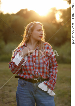 Contemplative Young Woman Standing Outdoors During Sunset With Warm Rim Light And Relaxed Pose Contemplative Young Woman Standing Outdoors During Sunset With Warm Rim Light And Relaxed Pose 138780286