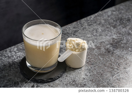 Protein vanilla shake in drinking glass and scoop with whey protein powder on dark background, copy space Protein vanilla shake in drinking glass and scoop with whey protein powder on dark background, copy space 138780326