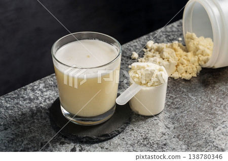 Protein vanilla shake in drinking glass and scoop with whey protein powder on dark background Protein vanilla shake in drinking glass and scoop with whey protein powder on dark background 138780346