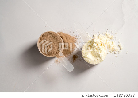 Vanilla and chocolate whey protein powder in scoops, food supplements, bright background Vanilla and chocolate whey protein powder in scoops, food supplements, bright background 138780358