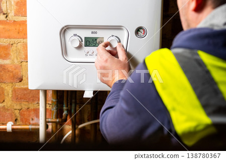 Men hand setting temperature button on control panel of central heating at combi boiler. Incressing price for gas Men hand setting temperature button on control panel of central heating at combi boiler. Incressing price for gas 138780367