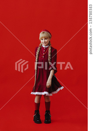 Caucasian girl in red folk dress with braids standing on red background Caucasian girl in red folk dress with braids standing on red background 138780383