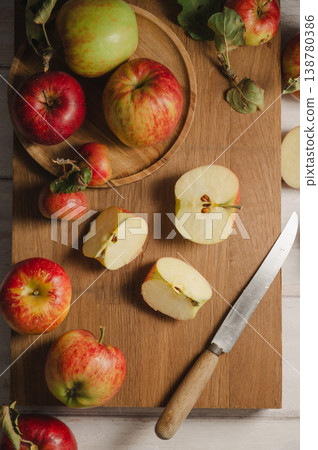 Red apples, whole and sliced on a wooden cutting board, lifestyle, top view. Autumn abstract food background. 138780386
