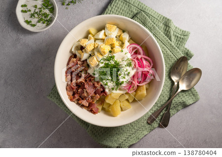 Egg potato salad with bacon and fresh herbs in a plate 138780404