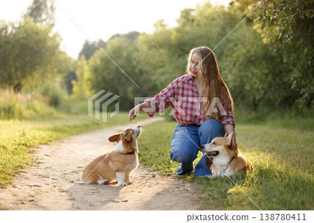 Female Rewards Dog During Training. Woman Gives Treat To Her Dog During Sunset Training Session 138780411