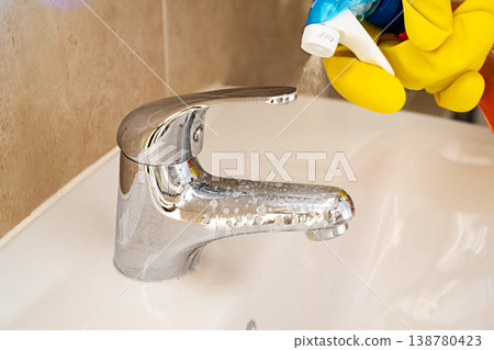 Cleaning bathroom water tap, yellow gloves and spray detergent 138780423