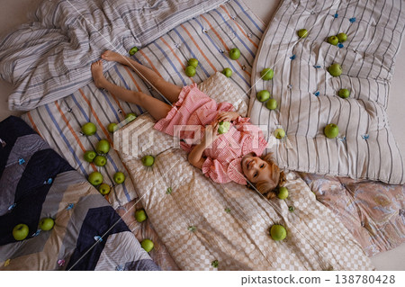 Little girl lying on mattresses with green apples, top view, princess and the pea concept Little girl lying on mattresses with green apples, top view, princess and the pea concept 138780428