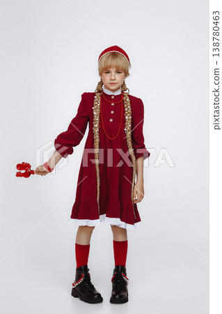 Smiling Caucasian girl with rooster lollipop in red folk style dress on light background Smiling Caucasian girl with rooster lollipop in red folk style dress on light background 138780463